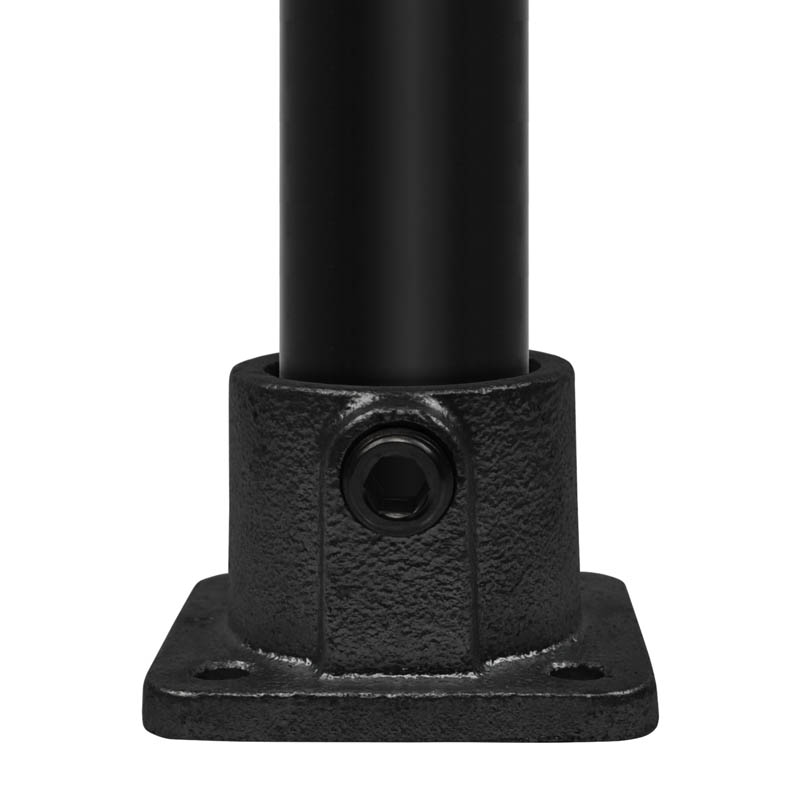Plaque de base noire, angulaire, avec une surface rugueuse et texturée. Un tube métallique noir passe verticalement à travers un manchon cylindrique central. Une vis à six pans creux latérale fixe solidement le tube. Plaque avec 4 trous de montage.