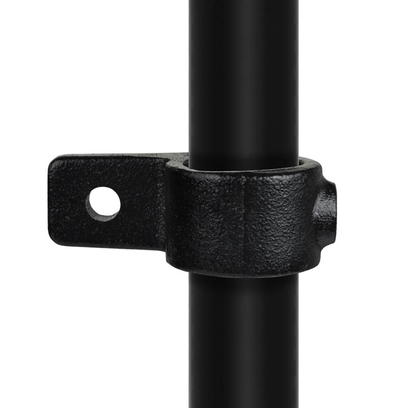 Pieza de ojal negra con textura mate, con una lengüeta plana única y una abertura redonda, firmemente sujeta a un tubo vertical liso de color negro. Este conector de tubos resistente a la corrosión sirve para fijar placas de forma segura a los tubos.
